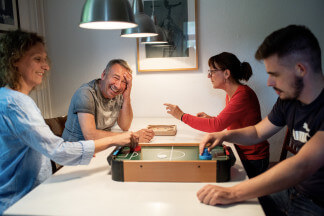 Meta Quark Haus vier Personen spielend am Tisch